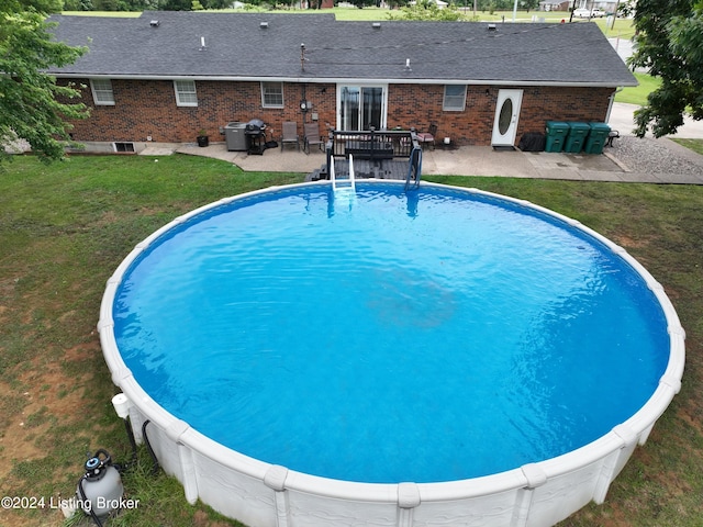 view of pool with a patio area and a lawn