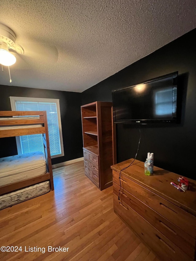 bedroom featuring ceiling fan, a textured ceiling, and wood-type flooring