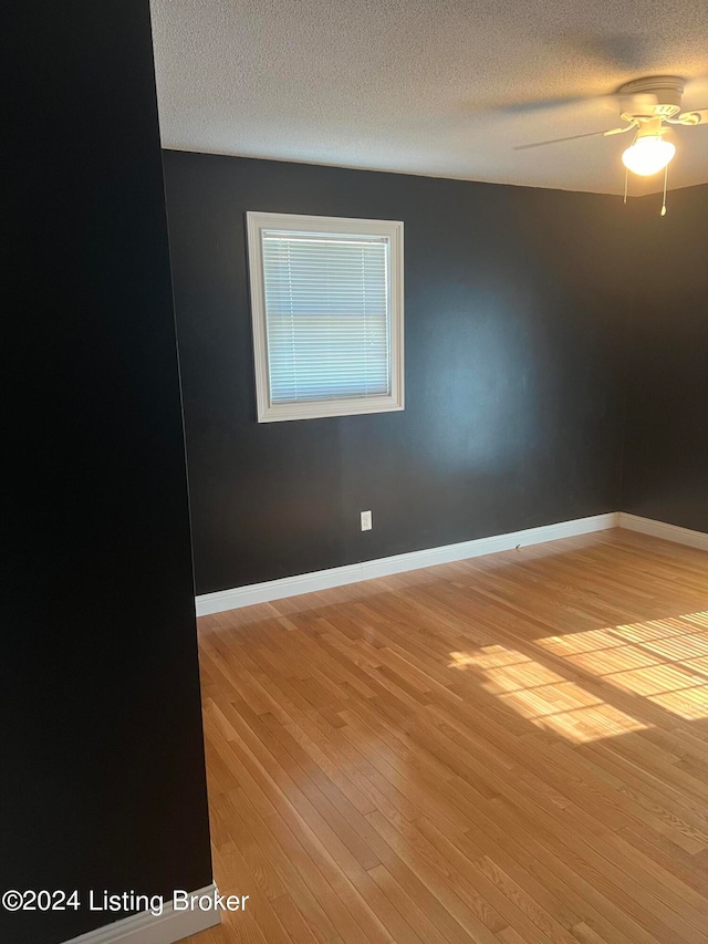 empty room with a textured ceiling, ceiling fan, and wood-type flooring