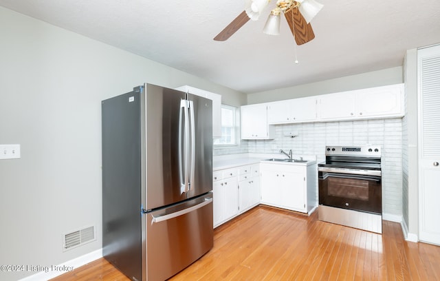 kitchen featuring backsplash, white cabinetry, light hardwood / wood-style floors, ceiling fan, and stainless steel appliances