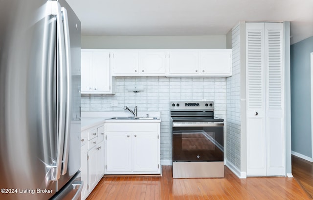 kitchen with light hardwood / wood-style floors, sink, stainless steel appliances, and white cabinets