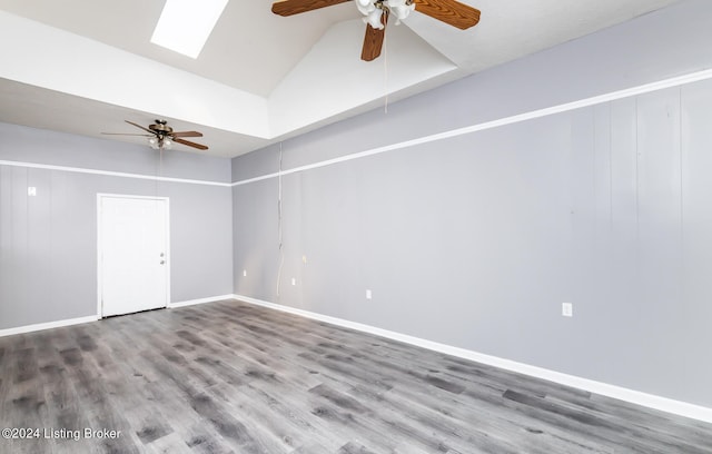 empty room with a towering ceiling, ceiling fan, a skylight, and wood-type flooring