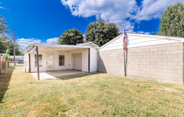 rear view of property with ceiling fan, a patio area, and a yard