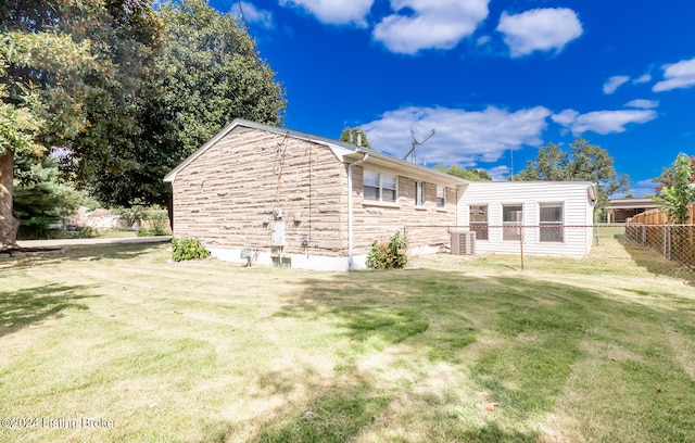 back of house with central AC unit and a yard