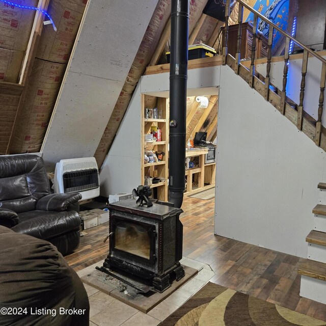 living room featuring vaulted ceiling, wood-type flooring, and a wood stove