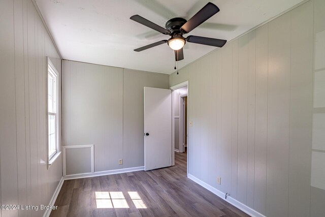 unfurnished room featuring light wood-type flooring, wood walls, and ceiling fan