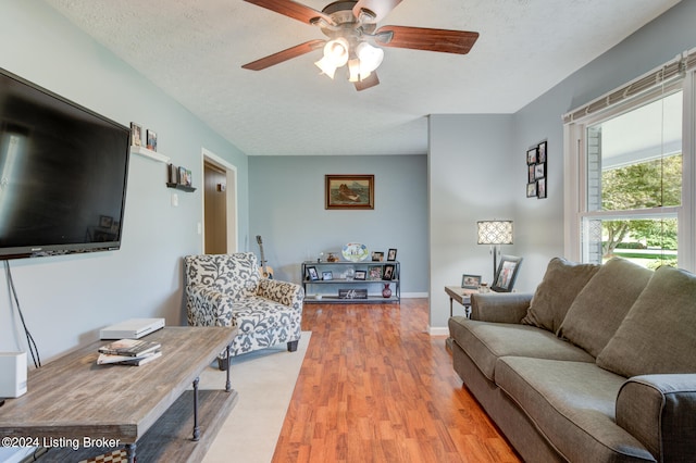 living room with a textured ceiling, ceiling fan, and wood-type flooring