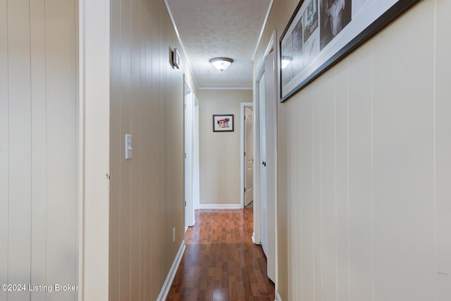 hall featuring dark hardwood / wood-style flooring, a textured ceiling, and crown molding