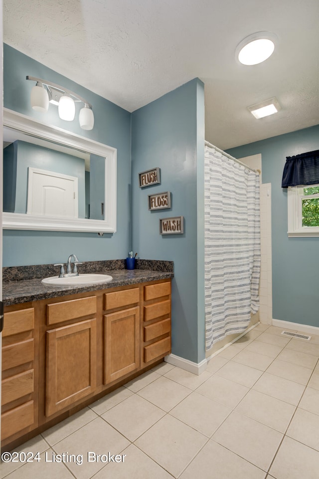 bathroom with tile patterned flooring, walk in shower, and vanity