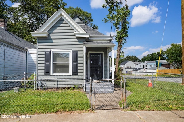 shotgun-style home featuring a front lawn, a shingled roof, fence private yard, and a gate