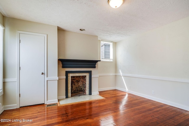 unfurnished living room with hardwood / wood-style flooring and a textured ceiling