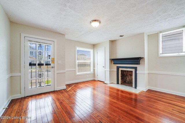 unfurnished living room with hardwood / wood-style floors and a textured ceiling