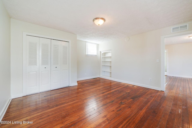 unfurnished bedroom featuring a closet, a textured ceiling, and hardwood / wood-style floors