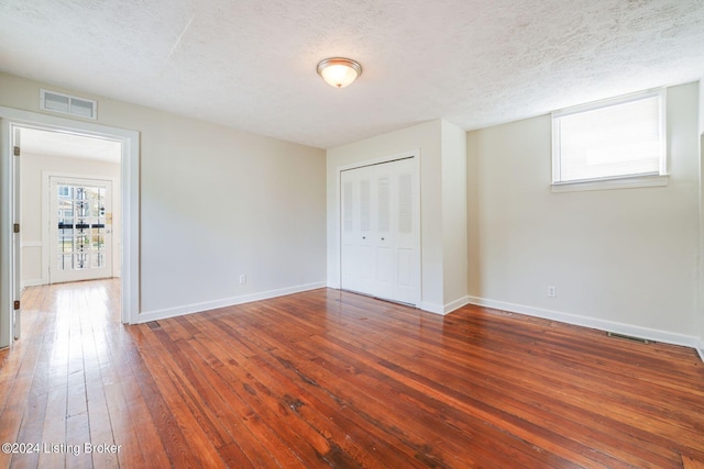 unfurnished room with hardwood / wood-style floors and a textured ceiling