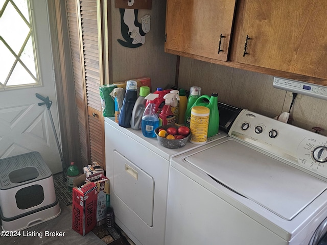 clothes washing area featuring cabinets and washer and clothes dryer