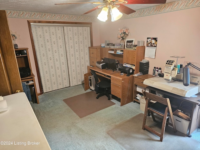 home office with a textured ceiling, ceiling fan, and carpet