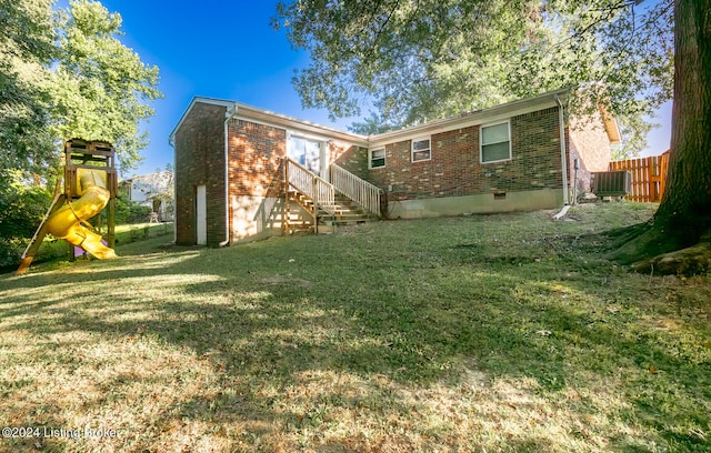 back of house with central AC, a playground, and a lawn