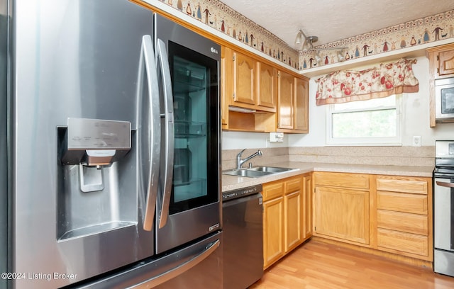 kitchen featuring sink, a textured ceiling, appliances with stainless steel finishes, and light hardwood / wood-style floors