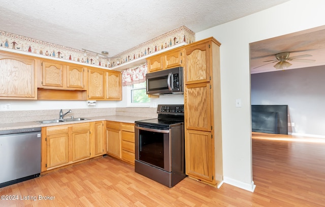 kitchen with appliances with stainless steel finishes, sink, light wood-type flooring, a textured ceiling, and ceiling fan