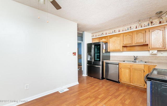 kitchen featuring appliances with stainless steel finishes, light hardwood / wood-style floors, sink, a textured ceiling, and ceiling fan