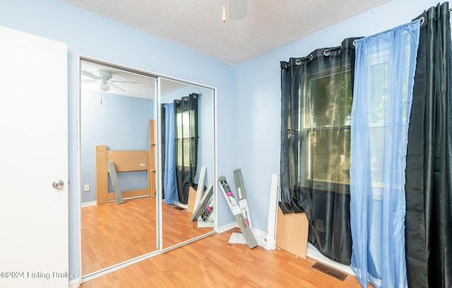 unfurnished bedroom featuring a textured ceiling, a closet, ceiling fan, and hardwood / wood-style flooring