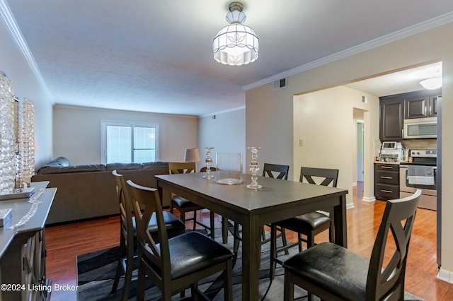 dining room with ornamental molding and hardwood / wood-style flooring