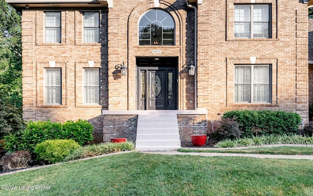 entrance to property with a yard and brick siding