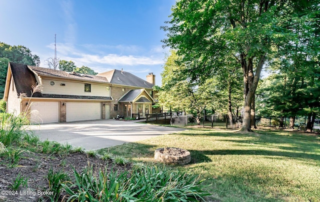 view of front of property featuring an outdoor fire pit, an attached garage, fence, driveway, and a front lawn