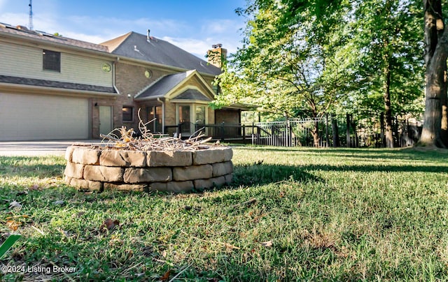 view of front of property featuring brick siding, a chimney, fence, a garage, and a front lawn