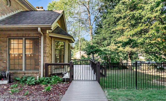 exterior space featuring brick siding, fence, a lawn, roof with shingles, and a gate