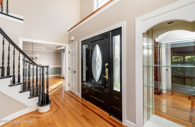 foyer featuring a wealth of natural light, an inviting chandelier, a towering ceiling, and light wood-type flooring