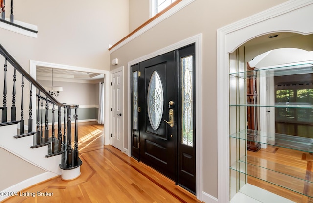 entryway with stairs, a healthy amount of sunlight, a towering ceiling, and light wood-style floors