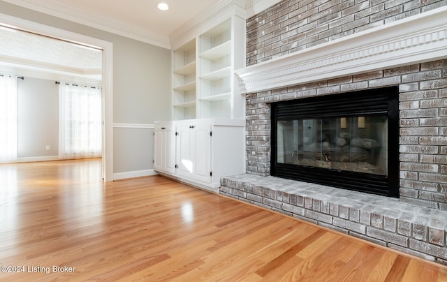 interior details with crown molding, hardwood / wood-style flooring, built in features, and a brick fireplace