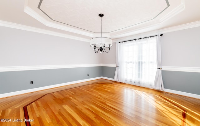 unfurnished room featuring a chandelier, wood-type flooring, and a raised ceiling