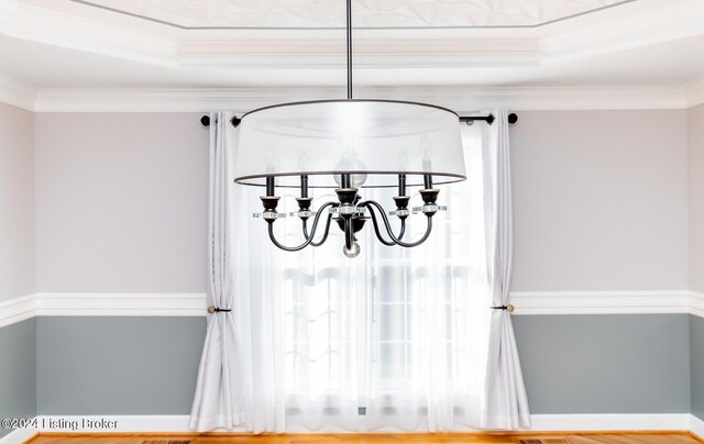 interior details with crown molding and a raised ceiling