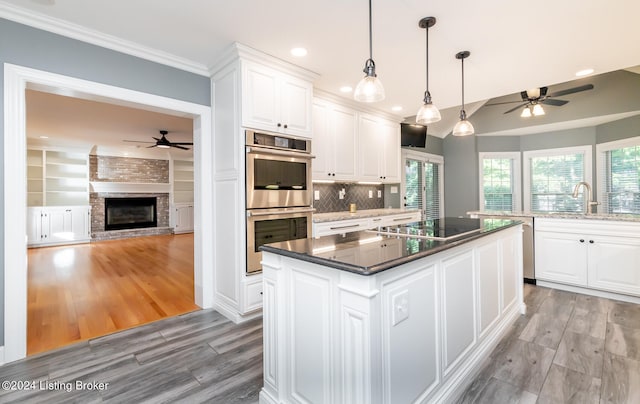 kitchen with stainless steel double oven, black electric stovetop, light hardwood / wood-style flooring, a center island, and white cabinetry