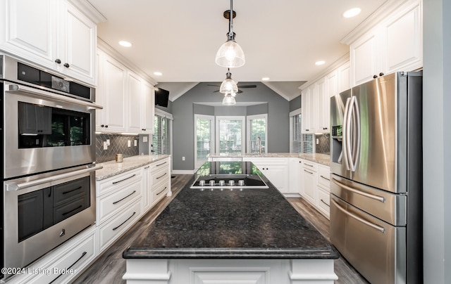 kitchen with kitchen peninsula, white cabinets, tasteful backsplash, stainless steel appliances, and a center island