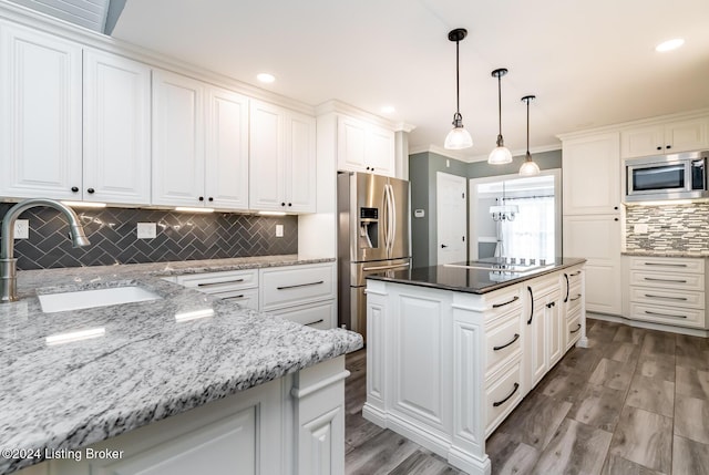 kitchen with dark stone counters, appliances with stainless steel finishes, a sink, and white cabinets