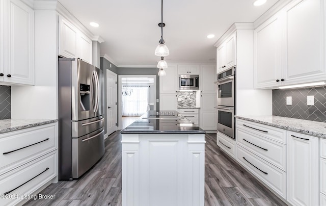 kitchen featuring dark stone counters, hanging light fixtures, appliances with stainless steel finishes, and white cabinets