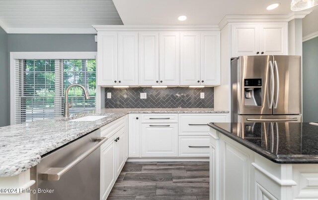 kitchen featuring stone countertops, ornamental molding, sink, white cabinets, and appliances with stainless steel finishes