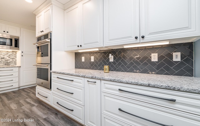 kitchen featuring decorative backsplash, white cabinets, appliances with stainless steel finishes, light stone countertops, and dark hardwood / wood-style floors