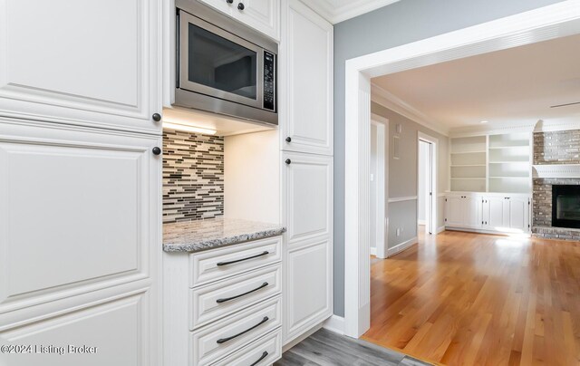 kitchen featuring light hardwood / wood-style flooring, stainless steel microwave, and white cabinets