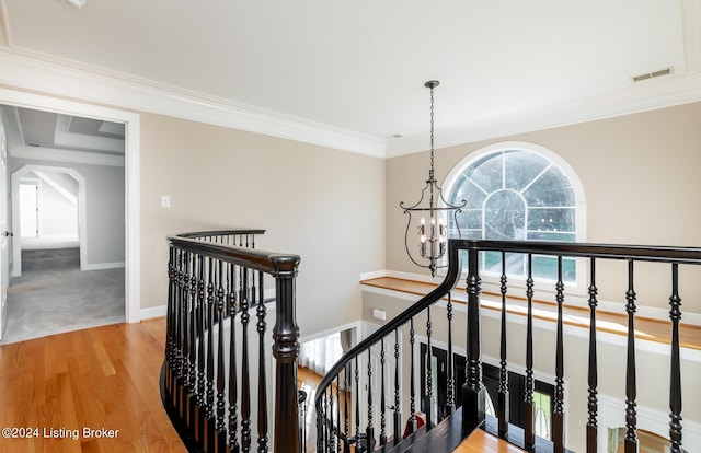 hall featuring visible vents, ornamental molding, wood finished floors, an upstairs landing, and a notable chandelier