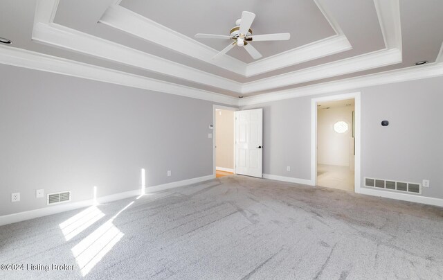 carpeted spare room with crown molding, a tray ceiling, and ceiling fan