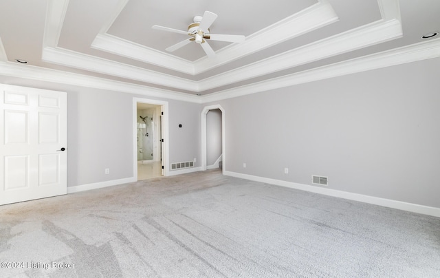 carpeted spare room with crown molding, ceiling fan, and a raised ceiling