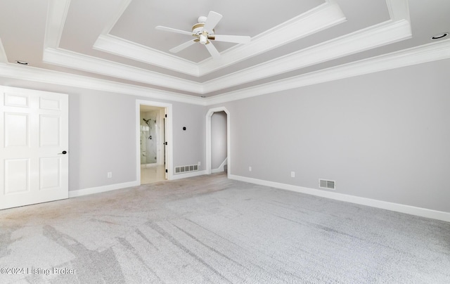 empty room featuring arched walkways, a tray ceiling, visible vents, and a ceiling fan