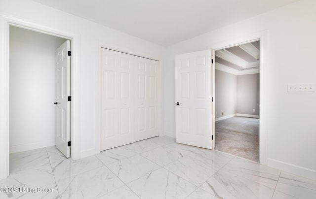 unfurnished bedroom featuring a closet, marble finish floor, and baseboards