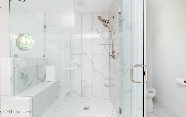 bathroom featuring a stall shower, marble finish floor, baseboards, and toilet