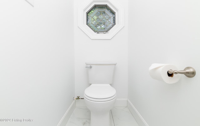 bathroom featuring marble finish floor, toilet, and baseboards