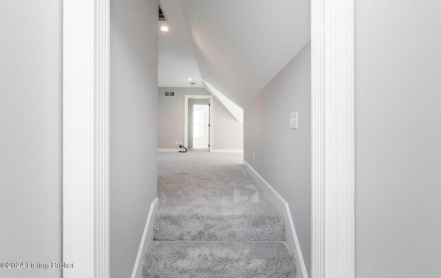 staircase featuring lofted ceiling and carpet floors